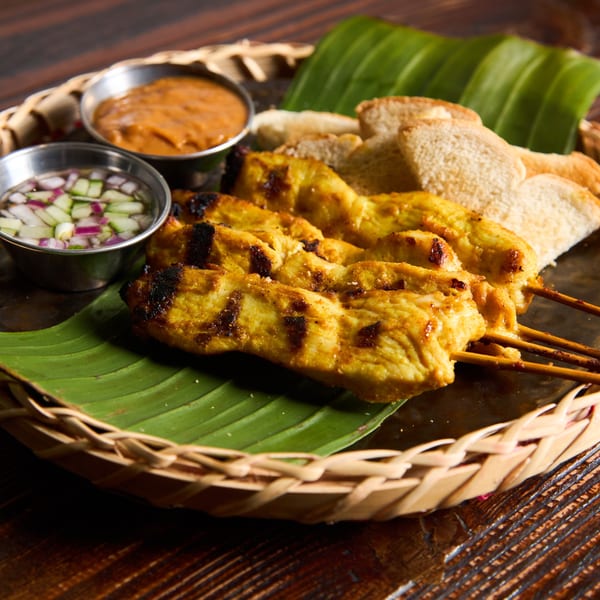 Kittiwat Thai Kitchen's chicken satay skewers with peanut sauce, cucumber relish, and toast on a banana leaf.