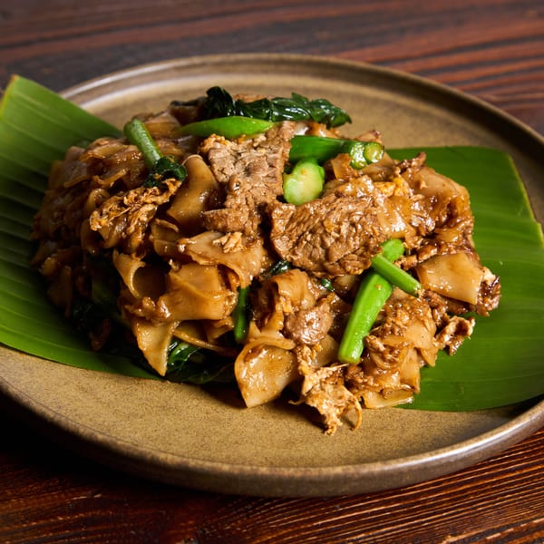 Kittiwat Thai Kitchen's Pad See Ew with wide noodles, beef, and green vegetables on a banana leaf.